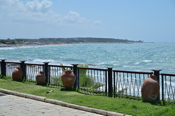 Walking path along the sea, fenced with a lattice with clay amphoras