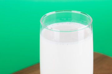A glass of milk in front of a green background