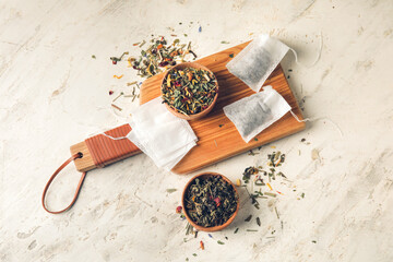 Tea bag and bowls with dry leaves on light background