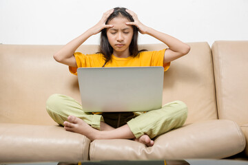 Asian little girl with laptop feeling stress for online school class at home