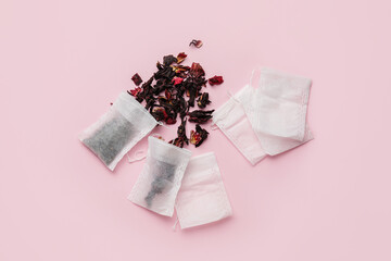 Tea bags with dry leaves on color background