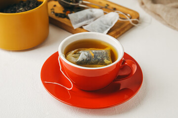 Cup with tea bag on light background