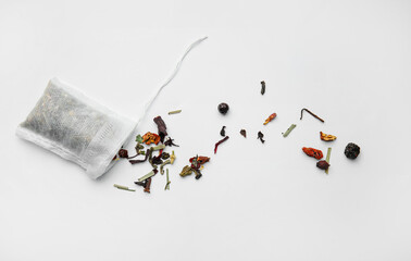 Tea bag with dry leaves on white background