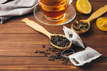 Tea bags with dry leaves on wooden background