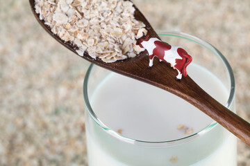 Oatmeal and wooden spoon and cow model on milk