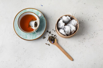 Tasty tea and bags with dry leaves on light background