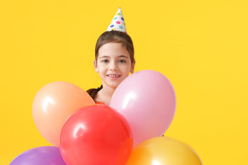 Fototapeta na wymiar Cute little girl with balloons celebrating Birthday on color background