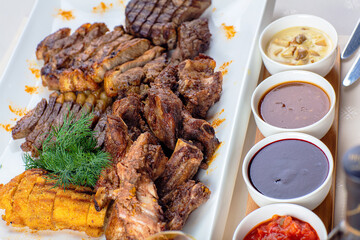 Assorted meat on a plate with sauces.