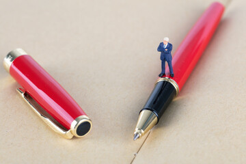Businessman doll standing on signature pen