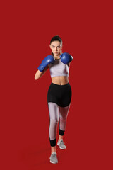 Sporty female coach in boxing gloves on color background