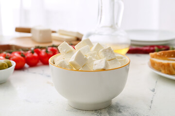 Bowl with pieces of feta cheese on light table in kitchen