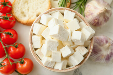 Board with pieces of feta cheese, tomato cherry, garlic and fresh bread on light table