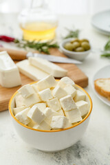 Bowl with pieces of feta cheese on light table