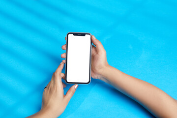 person holding mobile phone, lady using smart phone over blue background with white display for usage