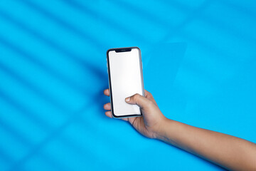 person holding mobile phone, lady using smart phone over blue background with white display for usage