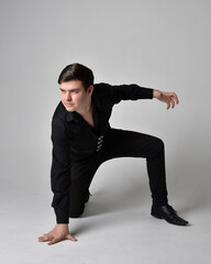 Full length portrait of a  brunette man wearing black shirt and gothic waistcoat.  Seated  pose...