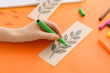 Woman coloring bookmark on color background
