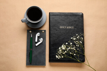 Holy Bible, cup of coffee, earphones and flowers on color background