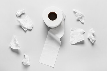 Roll of toilet paper and crumpled sheets on grey background