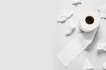 Roll of toilet paper and crumpled sheets on grey background