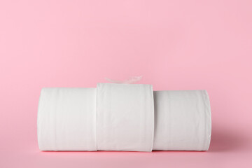 Rolls of toilet paper and feather on color background