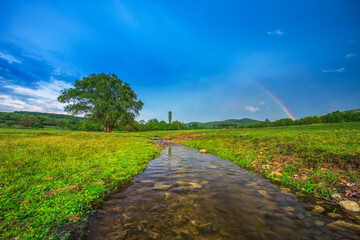 Rainbow over fields and trees and river