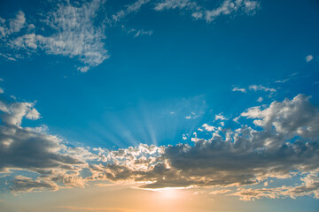 Naklejka na ściany i meble Sunset dramatic sky clouds with sunbeam
