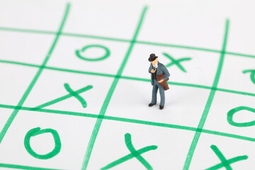 Miniature businessman facing a choice on a checkered graph
