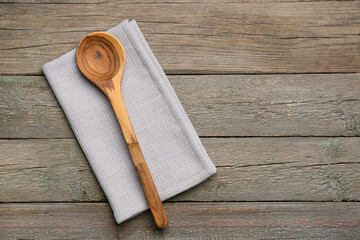 Fabric napkin and spoon on wooden background