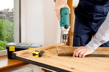 Handyman in blue uniform works with electricity automatic screwdriver. House renovation conception.