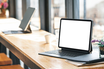 Blank screen tablet with keyboard on wooden counter table in cafe.