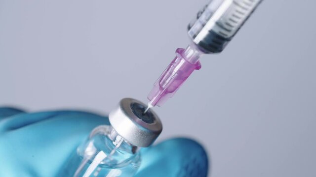 Close up shot of injection needle suck up transparent medicine into syringe, medicine in vial, ready for vaccine injection, administration of serum system, coronavirus vaccine distribution supply cure
