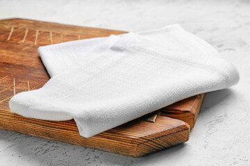Fabric napkin and wooden board on light background