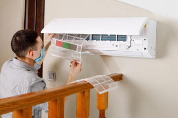 Male technician cleaning air conditioner indoors
