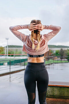 Unrecognizable young female athlete stretching neck and shoulders outdoors