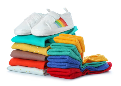 Stack of baby clothes and shoes on white background