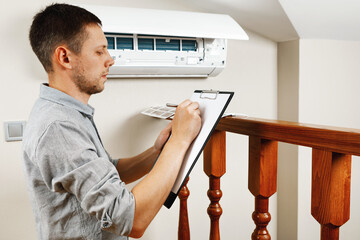 Male technician cleaning air conditioner indoors