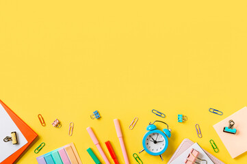 Education, back to school, freelancer work concept. School supplies, stationery accessories along bottom edge on yellow background. Flat lay, top view. Copy space