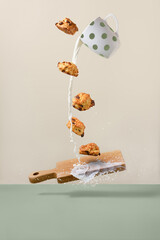 Levitating cookies over wooden board and milk flowing out of the cup