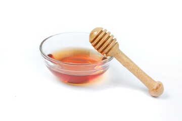 pure honey glass bowl with honey wooden spoon isolated on white background Clipping path.