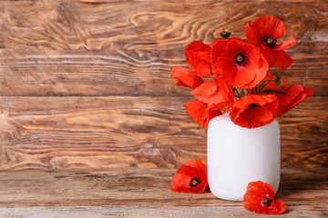 Vase with beautiful red poppy flowers on wooden background