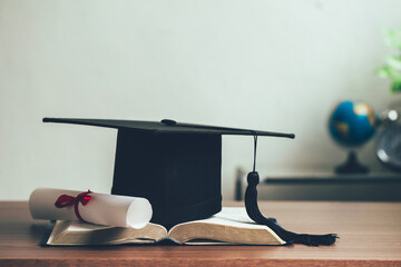 A mortarboard and graduation scroll on open books on the desk.education learning concept