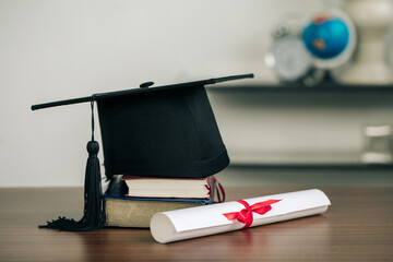 A mortarboard on books and graduation scroll on the desk.education learning concept - obrazy, fototapety, plakaty