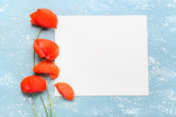 Beautiful red poppy flowers and paper sheet on color background