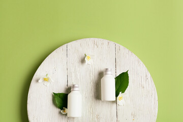 Tray with bottles of cosmetic products  and jasmine flowers on color background
