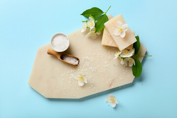 Composition with soap bars, sea salt and jasmine flowers on color background