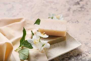 Composition with soap bars and jasmine flowers on grunge background