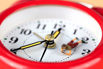 Miniature figures reading a book on an alarm clock