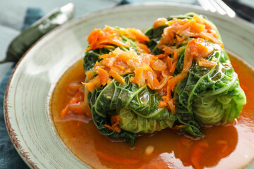 Plate with stuffed cabbage leaves with tomato sauce on table, closeup