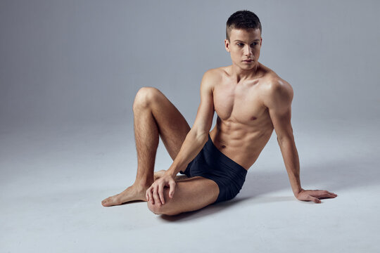 sporty man muscled body posing sitting on workout floor